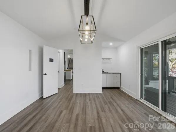 a view of an empty room with window wooden floor and chandelier