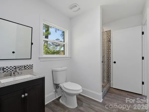 a bathroom with a granite countertop toilet a sink and a shower