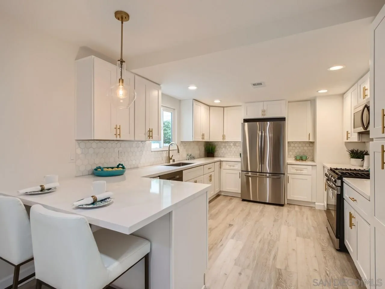 a kitchen with a sink a refrigerator a stove and white cabinets with wooden floor