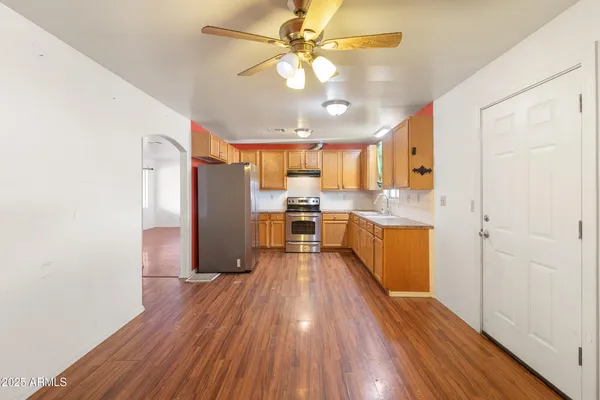 a view of a kitchen with wooden floor a sink and stainless steel appliances