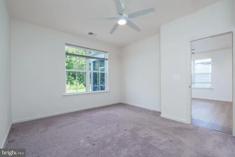 an empty room with a window and a ceiling fan