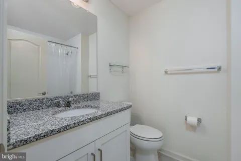 a bathroom with a granite countertop sink a toilet and a mirror