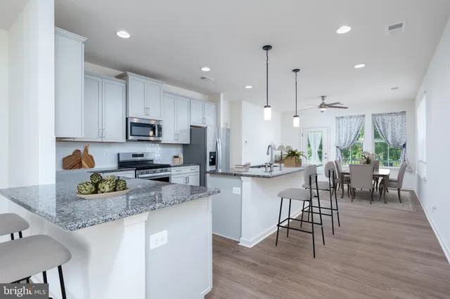 a kitchen with kitchen island granite countertop wooden floors cabinets and appliances