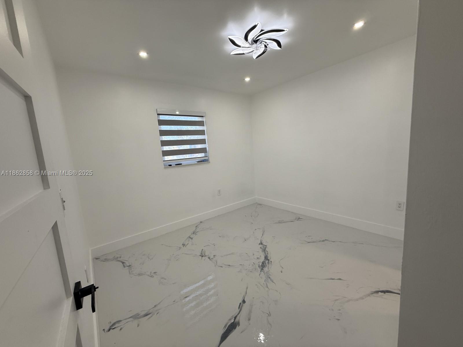 11805 Southwest 185th Street Miami, FL 33177 - Photo 11 of 28 an empty room with a chandelier fan and windows