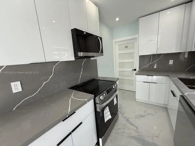 an empty room with a chandelier fan and windows