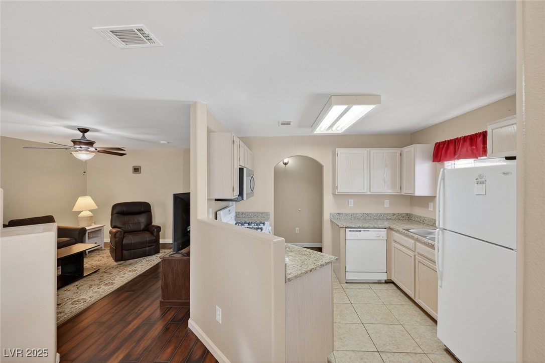 698 South Racetrack Road, Unit 1222 Henderson, NV 89015 - Photo 31 of 31 Kitchen with arched walkways, white appliances, open floor plan, a ceiling fan, and light stone countertops