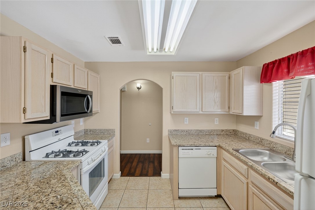 698 South Racetrack Road, Unit 1222 Henderson, NV 89015 - Photo 11 of 31 Kitchen featuring white appliances, light brown cabinetry, arched walkways, and light tile patterned floors