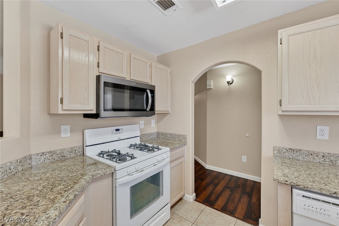 698 South Racetrack Road, Unit 1222 Henderson, NV 89015 - Photo 12 of 31 Kitchen with white appliances, light brown cabinetry, light stone counters, and arched walkways