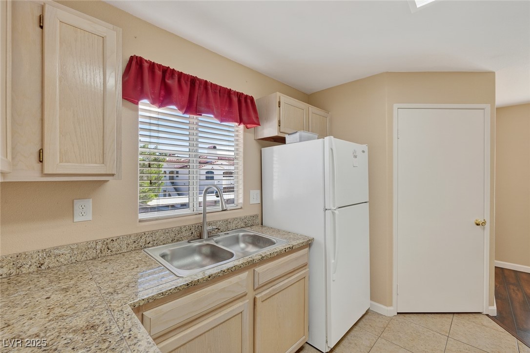 698 South Racetrack Road, Unit 1222 Henderson, NV 89015 - Photo 13 of 31 Kitchen featuring light brown cabinets, freestanding refrigerator, light tile patterned flooring, and light stone countertops