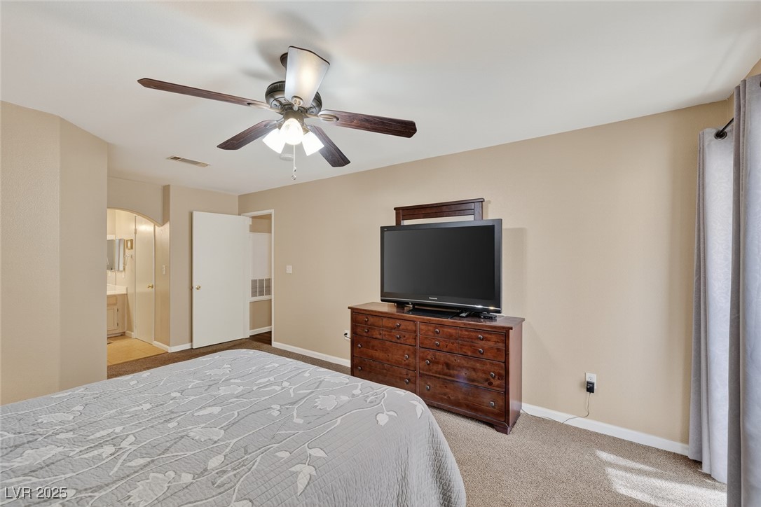 698 South Racetrack Road, Unit 1222 Henderson, NV 89015 - Photo 17 of 31 Bedroom with light colored carpet, ceiling fan, ensuite bath, and arched walkways