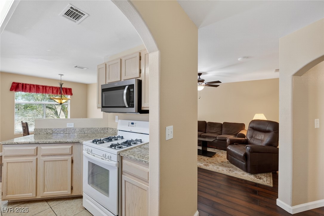 698 South Racetrack Road, Unit 1222 Henderson, NV 89015 - Photo 9 of 31 Kitchen with arched walkways, light brown cabinetry, white range with gas cooktop, stainless steel microwave, and a peninsula