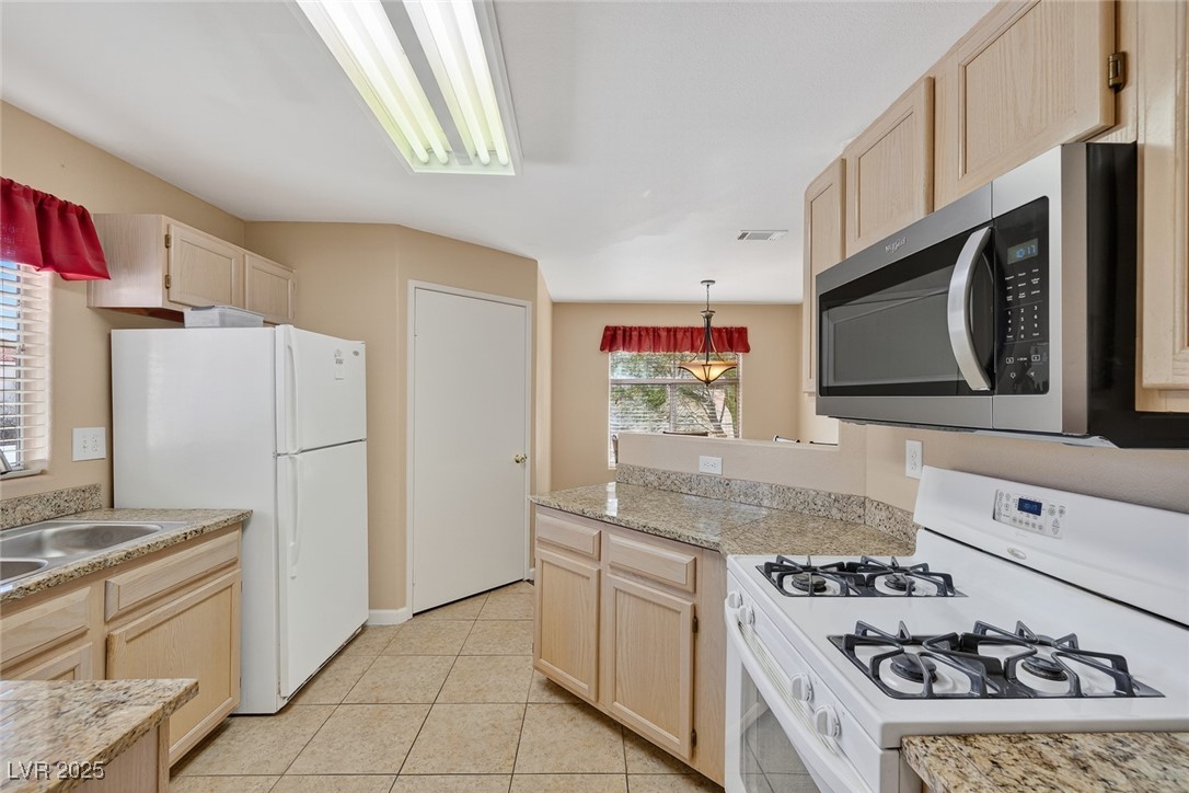698 South Racetrack Road, Unit 1222 Henderson, NV 89015 - Photo 10 of 31 Kitchen featuring light brown cabinetry, white appliances, a peninsula, light tile patterned flooring, and pendant lighting