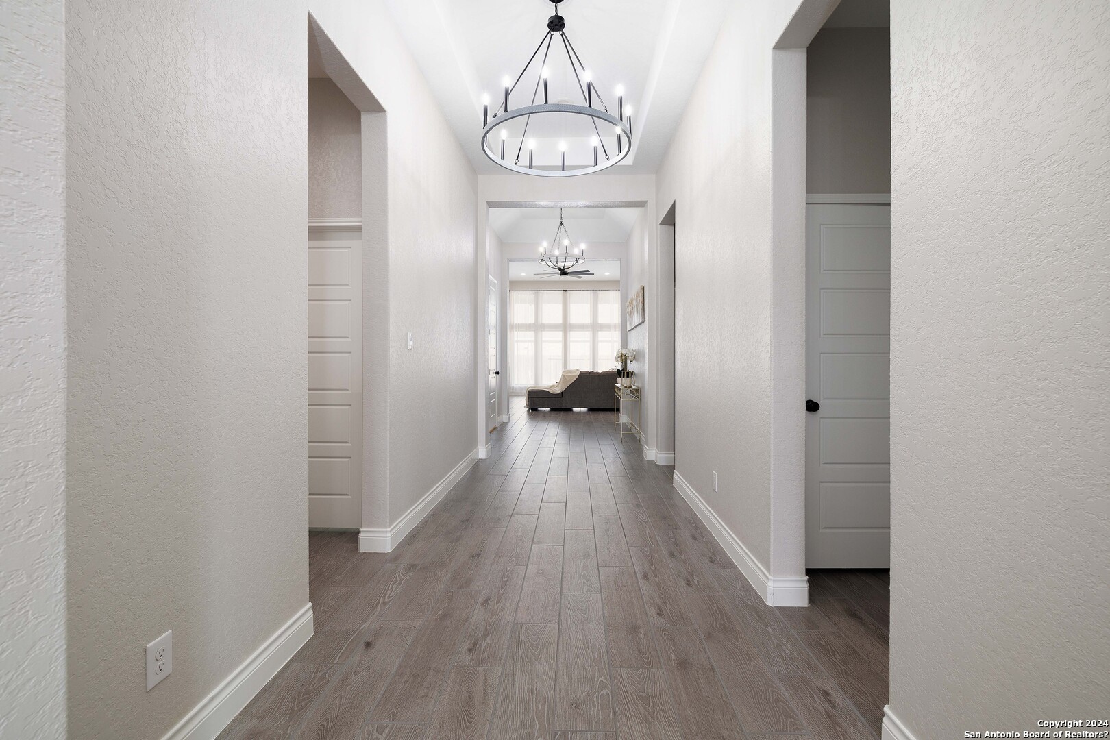 a view of a hallway with wooden floor and a chandelier