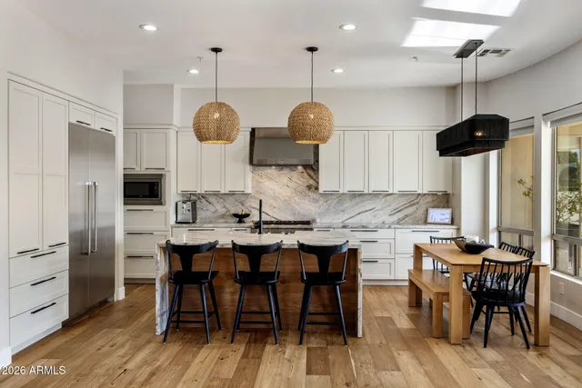 a kitchen with stainless steel appliances kitchen island a table and chairs in it