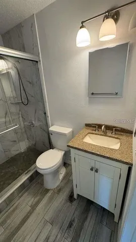 a bathroom with a granite countertop toilet sink and mirror