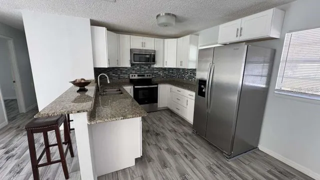 a kitchen with stainless steel appliances granite countertop a refrigerator a stove and a sink