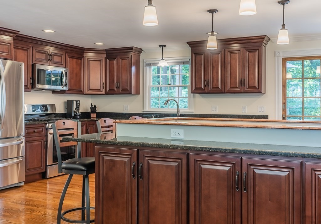 2 East Colonial Road Wilbraham, MA 01095 - Photo 6 of 42 a kitchen with stainless steel appliances granite countertop wooden cabinets a refrigerator a sink a stove a dining table and chairs