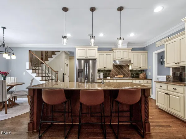 a kitchen with stainless steel appliances granite countertop a kitchen island a stove a table and chairs