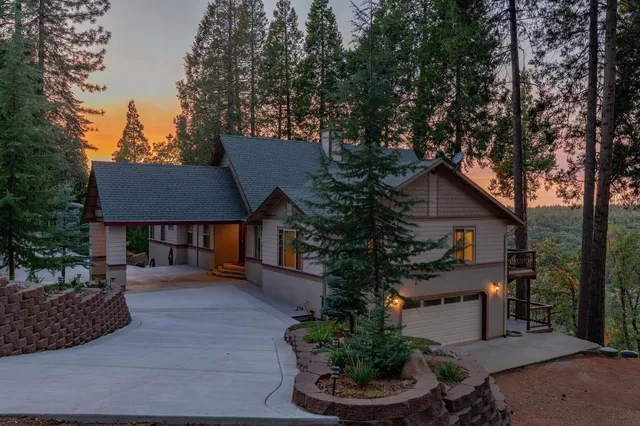a view of a house with large trees and wooden fence