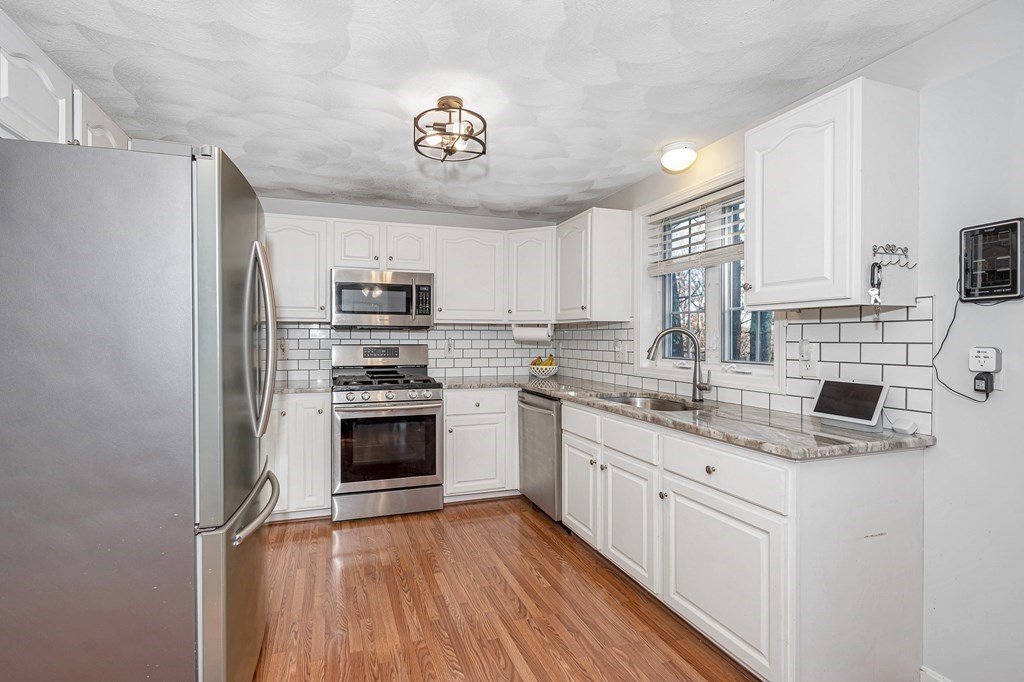 46 Parham Road Tyngsboro, MA 01879 - Photo 3 of 36 a kitchen with stainless steel appliances granite countertop white cabinets a sink a stove a microwave and cabinetry