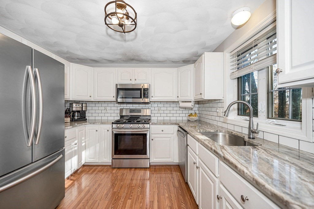 46 Parham Road Tyngsboro, MA 01879 - Photo 5 of 36 a kitchen with stainless steel appliances granite countertop a sink stove a refrigerator and a granite counter tops with wooden floors