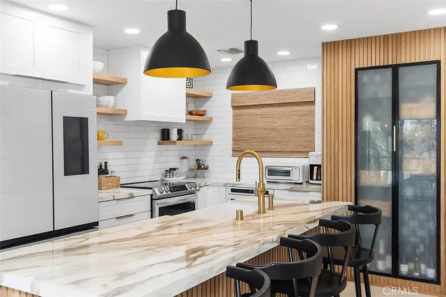 a kitchen with stainless steel appliances kitchen island granite countertop a table chairs in it and wooden floors