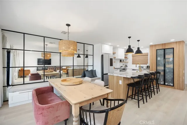 a dining hall with stainless steel appliances kitchen island granite countertop a dining table and chairs with wooden floor