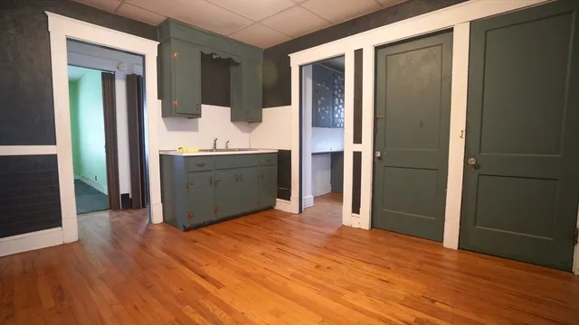 an empty room with kitchen view and wooden floor