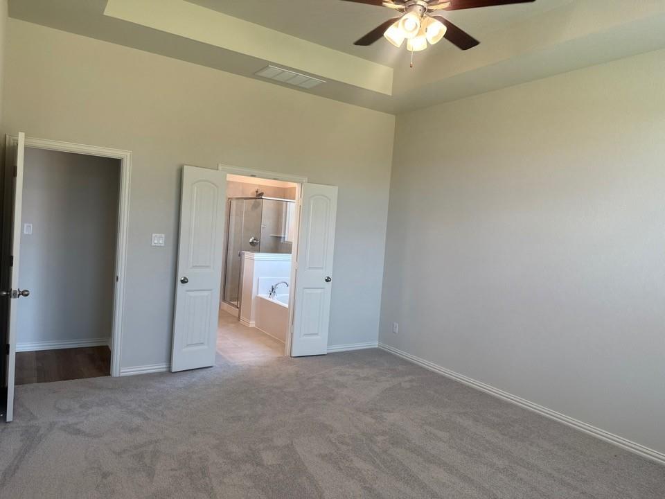 1233 Frio Drive Springtown, TX 76082 - Photo 7 of 13 Carpeted room featuring a ceiling fan with light fixture, tray ceiling, and neutral wall tones
