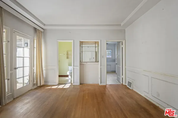 a view of empty room with wooden floor and fan