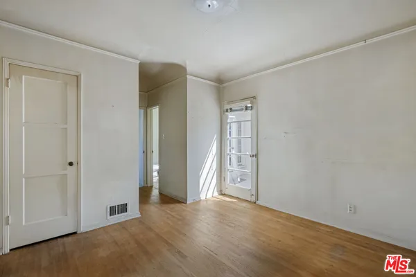 a view of an empty room with wooden floor and closet