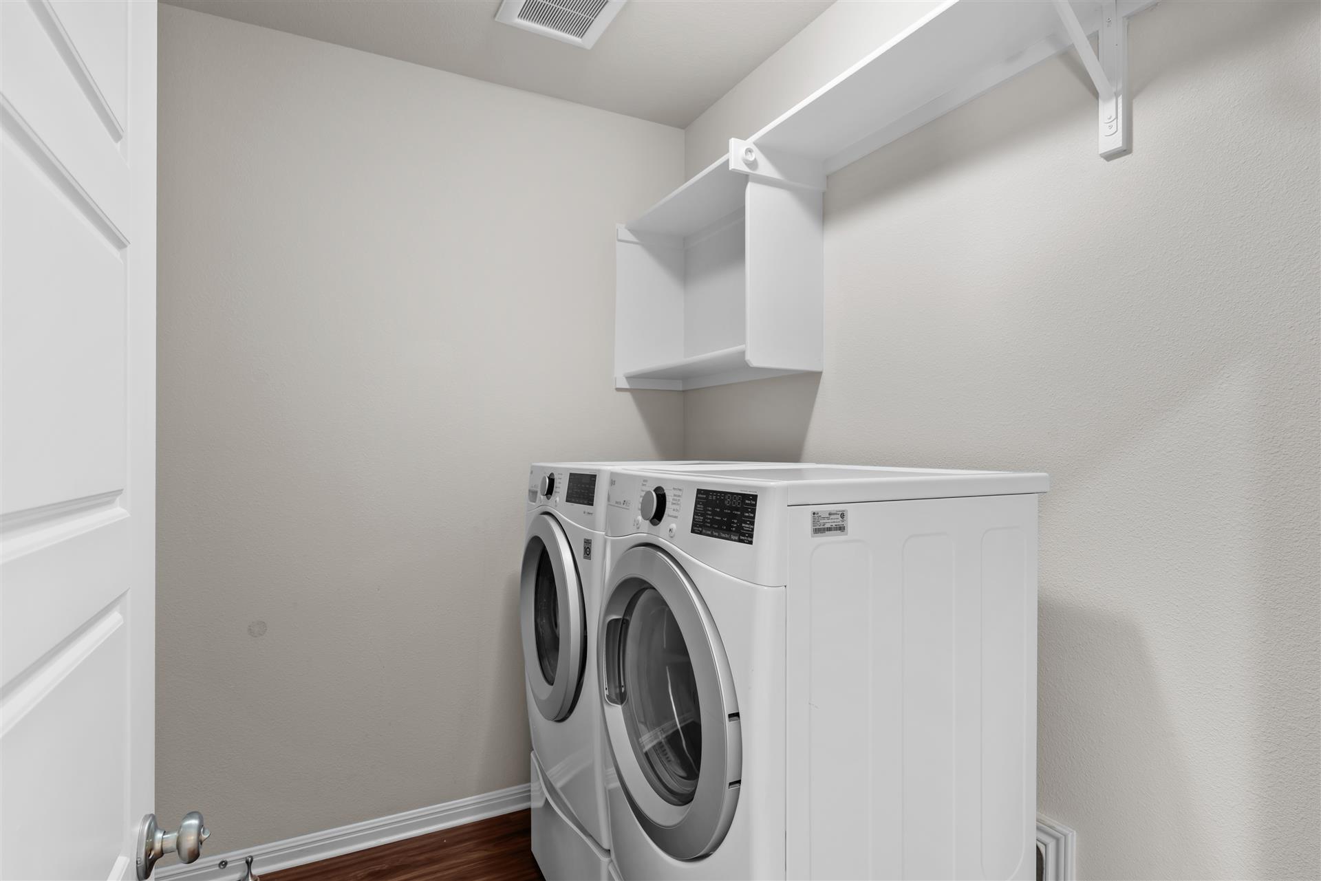 16512 Enamorado Road Manor, TX 78653 - Photo 20 of 31 A well-appointed utility area features a modern washer and dryer set, complemented by convenient overhead shelving.