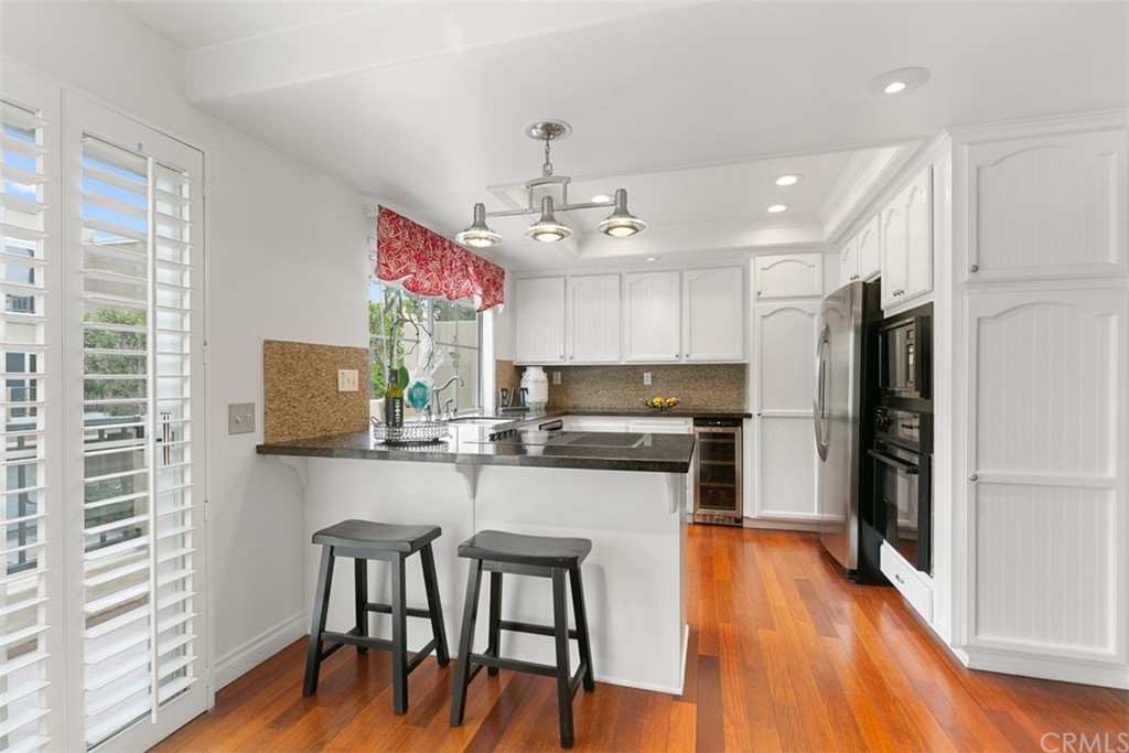 6051 Shadowbrook Circle Huntington Beach, CA 92648 - Photo 17 of 42 a kitchen with stainless steel appliances a dining table chairs refrigerator and microwave