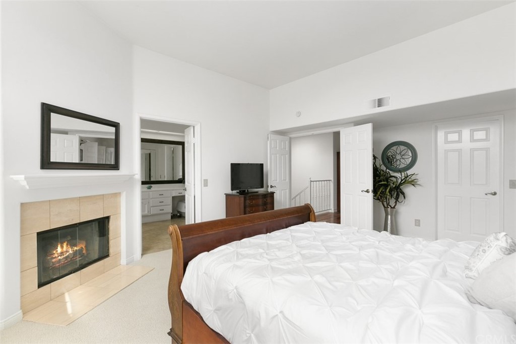 6051 Shadowbrook Circle Huntington Beach, CA 92648 - Photo 26 of 42 a bedroom with a bed and a fireplace
