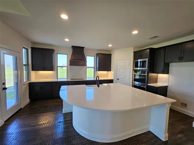 a large kitchen with kitchen island a stove a refrigerator a sink dishwasher with a dining table and wooden floor