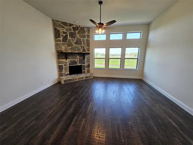 a view of a room with wooden floor fireplace and windows