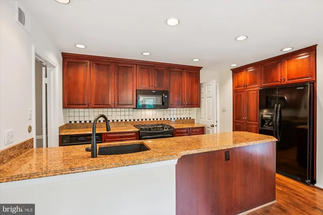 a kitchen with stainless steel appliances granite countertop a sink and a refrigerator