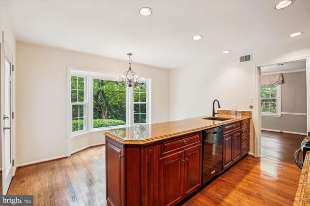 a kitchen with stainless steel appliances granite countertop a sink and wooden floors
