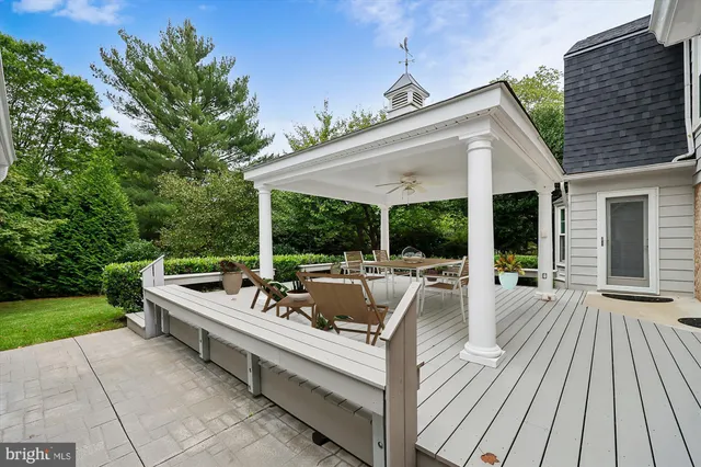 a view of a patio with couches table and chairs with wooden floor and fence