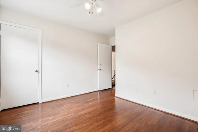 an empty room with wooden floor and fan
