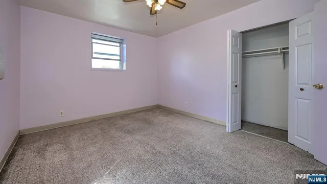 an empty room with a chandelier fan and windows