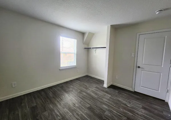 an empty room with wooden floor cabinet and windows