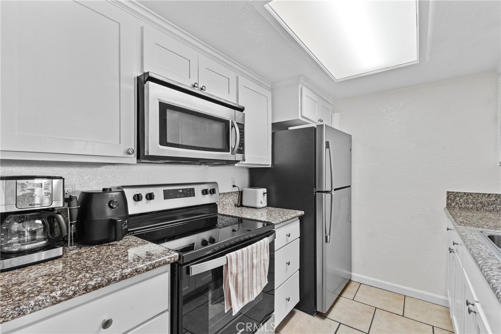 10151 Arrow Route, Unit 6 Rancho Cucamonga, CA 91730 - Photo 8 of 24 a kitchen with granite countertop a refrigerator stove and microwave