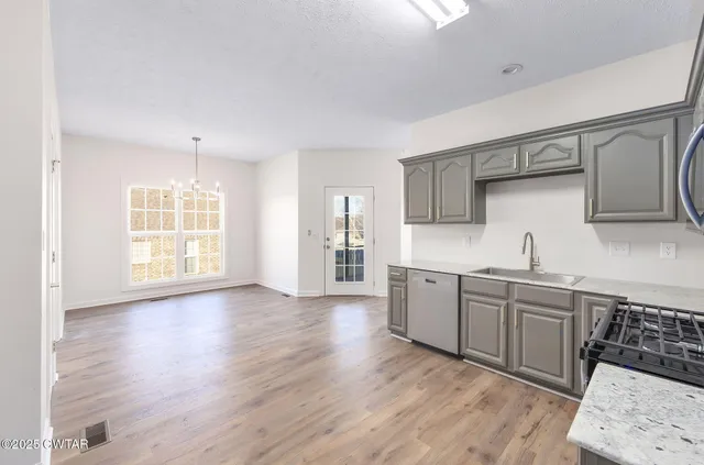 a kitchen with stainless steel appliances granite countertop a sink cabinets and wooden floor