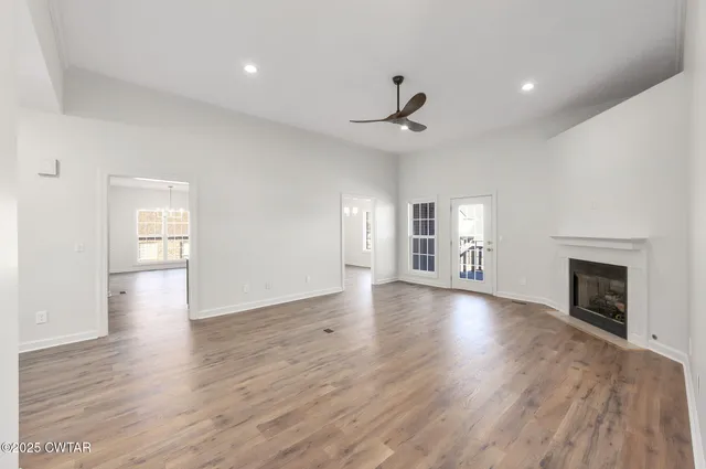 a view of an empty room with window and wooden floor