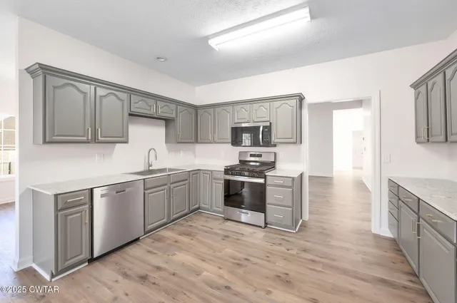 a kitchen with a sink cabinets and wooden floor