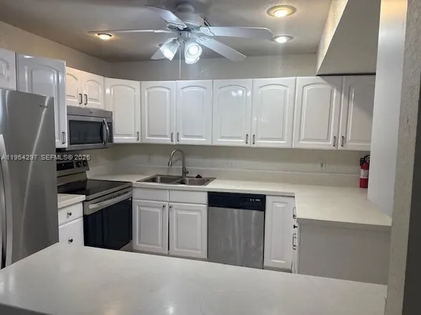 a kitchen with kitchen island white cabinets stainless steel appliances and sink