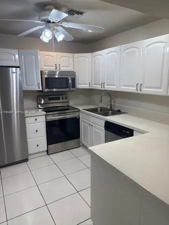 a kitchen with stainless steel appliances a sink a stove a refrigerator cabinets and chairs