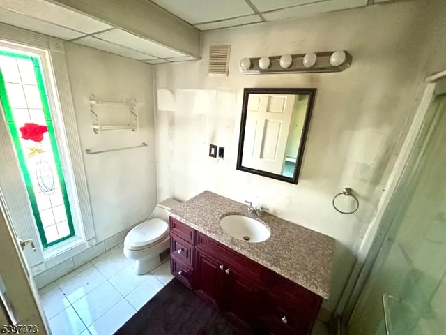 a bathroom with a granite countertop sink toilet a mirror and shower