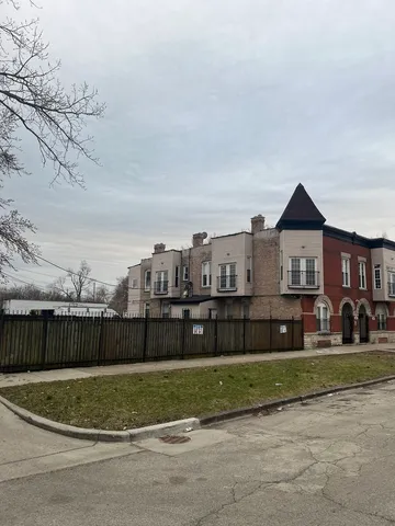 a view of a brick house next to a yard with wooden fence